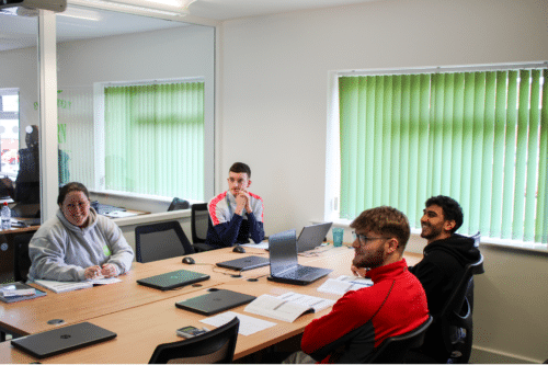 Apprentices sat round a table discussing apprenticeship wages