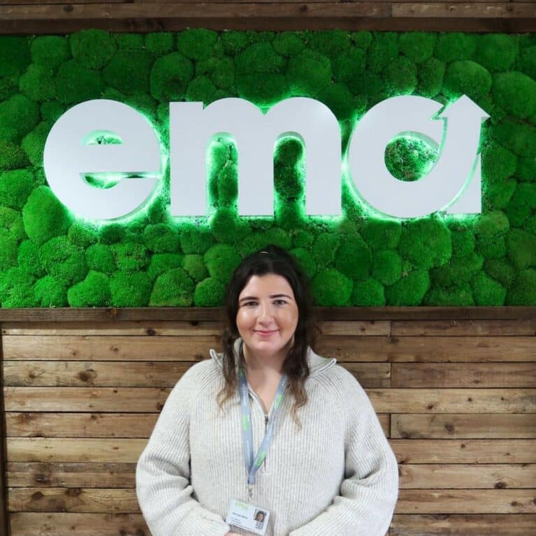 Portrait photograph of female staff member in front of company logo sign