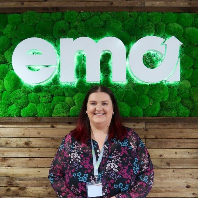 Portrait photograph of female staff member in front of company logo sign