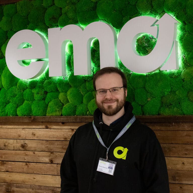 Photograph of Accountancy trainer, Tom standing in front of a green EMA sign